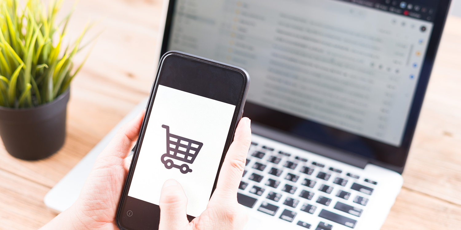 Online Shopping Website on Laptop. Shop by Smartphone, and Laptop. Close up Hands Using Smartphone Shopping Cart.<br />